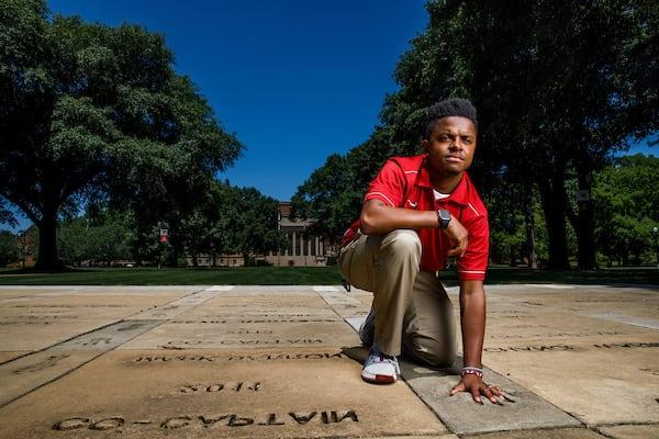 A student places their hand in the concrete handprints that surround denny chimes.